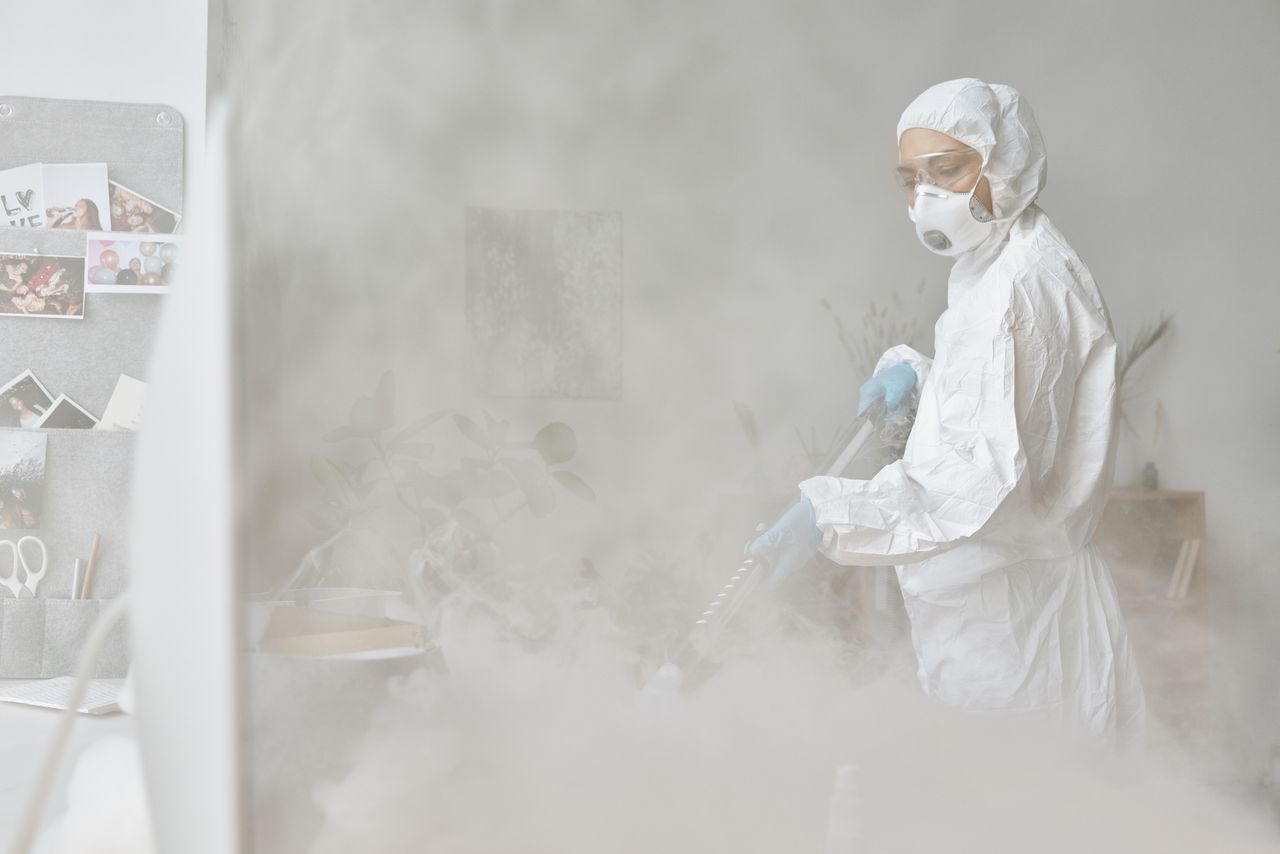 services-img A woman in a protective suit disinfects an indoor space with fogging equipment.